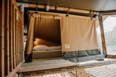 Binnenkant van een Ranger Lodge safaritent in Veluwepark de Bosgraaf, Nederland, met bed en hout.
