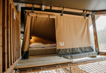 Interno di una tenda safari Ranger Lodge al Veluwepark de Bosgraaf nei Paesi Bassi, con letto visibile.