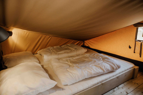 Binnenzicht op een comfortabele bed in de Ranger Lodge safaritent bij Veluwepark de Bosgraaf, Nederland.