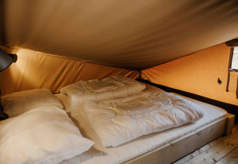 Indvendigt billede af en hyggelig seng i Ranger Lodge safari telt i Veluwepark de Bosgraaf, Holland.