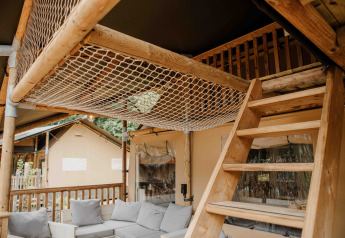 Interno della tenda safari Ranger Lodge al Veluwepark de Bosgraaf con soppalco e area salotto.