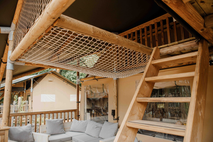 Innenraum des Ranger Lodge Safarizelts im Veluwepark de Bosgraaf mit Holztreppe und Sitzbereich.