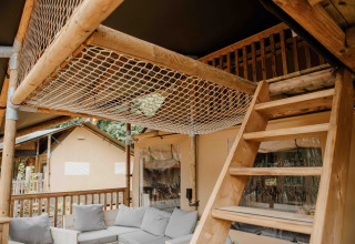 Innenraum des Ranger Lodge Safarizelts im Veluwepark de Bosgraaf mit Holztreppe und Sitzbereich.