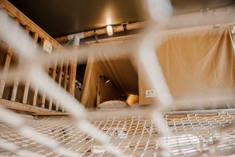 Vista a través de una red al área de dormir en una tienda safari Ranger Lodge, Veluwepark de Bosgraaf, Países Bajos.