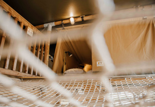 Blick durch ein Netz auf einen Schlafbereich im Safarizelt Ranger Lodge, Veluwepark de Bosgraaf, Niederlande.