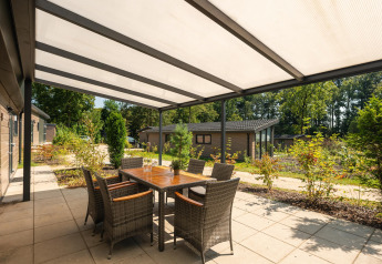 Terrasse extérieure couverte à Veluwe Lodge, Veluwepark de Bosgraaf, Pays-Bas, avec table et six chaises.
