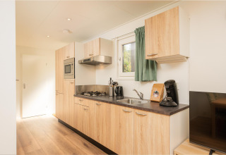 Cucina attrezzata nella Veluwe Lodge del Veluwepark de Bosgraaf, Paesi Bassi, con mobili in legno e elettrodomestici.