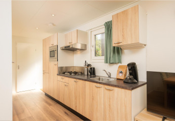 Well-equipped kitchen in Veluwe Lodge at Veluwepark de Bosgraaf, Netherlands, with wooden cabinets and appliances.
