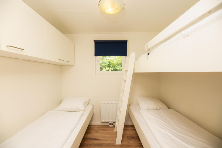 Zimmer mit zwei Einzelbetten, Etagenbett, Schränken und Fenster in der Veluwe Lodge, Veluwepark de Bosgraaf, Niederlande.