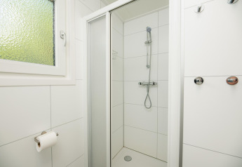 Doccia minimalista con piastrelle bianche, finestra e ganci alla Veluwe Lodge nei Paesi Bassi.