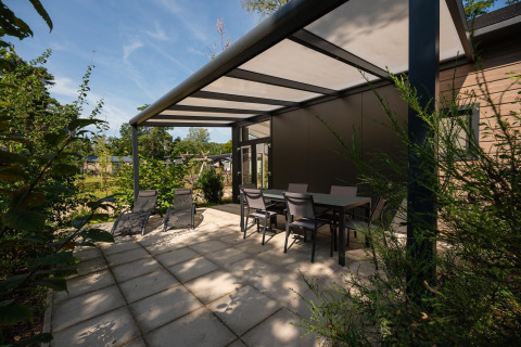Terrasse des Forest Lodge im Veluwe Park de Bosgraaf, Niederlande, mit Stühlen, Tisch und Liegen