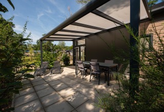 Terraza exterior en Forest Lodge, Veluwe park de Bosgraaf, Países Bajos, con sillas, mesa y tumbonas
