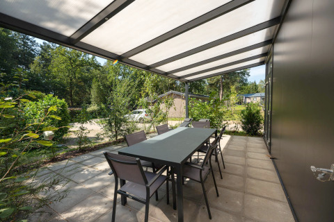 Terrasse extérieure couverte avec table et chaises à Forest Lodge au Veluwepark de Bosgraaf, Pays-Bas.