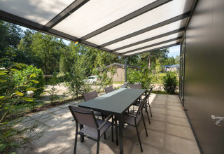 Terrasse extérieure couverte avec table et chaises à Forest Lodge au Veluwepark de Bosgraaf, Pays-Bas.