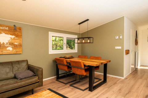 Salle à manger moderne avec table en bois, chaises en cuir et décoration murale à Forest Lodge au Veluwepark de Bosgraaf, Pays-Bas.