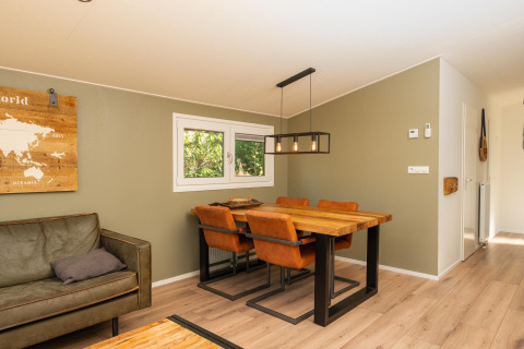 Salle à manger moderne avec table en bois, chaises en cuir et décoration murale à Forest Lodge au Veluwepark de Bosgraaf, Pays-Bas.