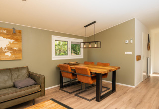 Moderne spiseplads med træbord, læderstole og vægkunst i Forest Lodge på Veluwepark de Bosgraaf, Holland.