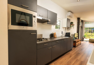 Cuisine moderne avec armoires grises à Forest Lodge, Veluwepark de Bosgraaf, Pays-Bas. Intérieur lumineux et spacieux.