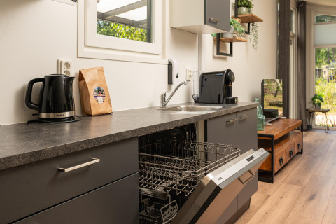 Cocina moderna en Forest Lodge, Veluwepark de Bosgraaf, Países Bajos, con lavavajillas abierto.