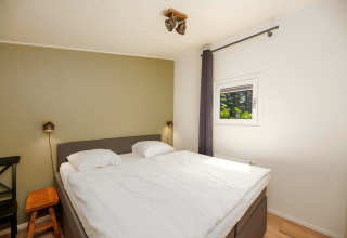 Chambre à Forest Lodge au Veluwepark de Bosgraaf, Pays-Bas, avec lit double et fenêtre lumineuse.