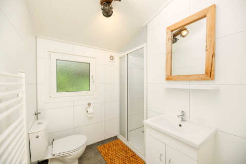 Salle de bain lumineuse à Forest Lodge au Veluwepark de Bosgraaf avec douche, miroir et toilettes blanches.