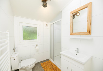 Helles Badezimmer in der Forest Lodge im Veluwepark de Bosgraaf mit Dusche, Spiegel und Toilette.