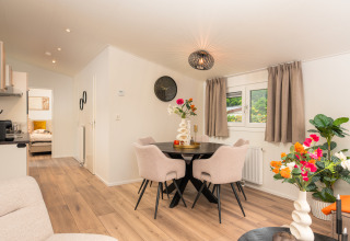 Modern stue og spisestue i Forest Lodge på Veluwepark de Bosgraaf, Holland, med lyse møbler og blomster.