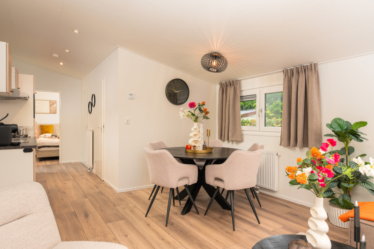Bright living and dining area in Forest Lodge at Veluwepark de Bosgraaf, Netherlands, with stylish decor and flowers.