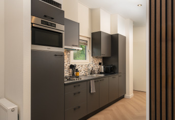 Cucina moderna in lodge con mobili scuri, forno a incasso, piano cottura, lavello e elettrodomestici vicino alla finestra.