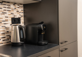 Kaffeemaschine und Wasserkocher auf schwarzer Arbeitsplatte vor Mosaikfliesen in einer Lodgeküche.