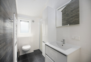 Salle de bains moderne au lodge Loevestein du Veluwepark de Bosgraaf, aux Pays-Bas, décor blanc élégant.