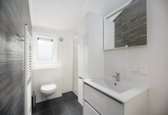 Salle de bains moderne au lodge Loevestein du Veluwepark de Bosgraaf, aux Pays-Bas, décor blanc élégant.