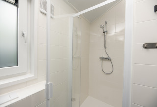 Ducha moderna con azulejos blancos y puerta de cristal en Lodge Loevestein, Veluwepark de Bosgraaf, Países Bajos.