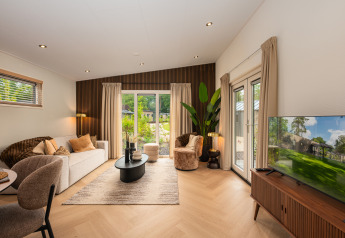 Modernes Lodge-Wohnzimmer mit eleganter Einrichtung, Holzwand und großen Fenstern mit Naturblick.