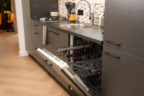 Moderne køkken med integreret opvaskemaskine, åben låge og vask, taget i en hyggelig lodge.