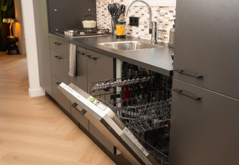 Modern kitchen with built-in dishwasher open, visible sink and countertop, taken inside a cozy lodge.