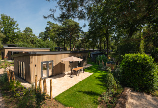Moderne Loevestein-lodge met buitenjacuzzi, zonnig terras en groene tuin in bosrijke omgeving.