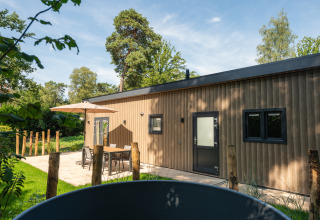 Udendørs foto af Loevestein-lodge med hot tub og terrasse ved Veluwepark de Bosgraaf i Holland.