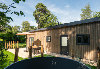 Außenaufnahme der Lodge Loevestein mit Whirlpool und Terrasse im Veluwepark de Bosgraaf, Niederlande.