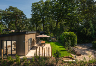 Lodge Loevestein met hot tub en terras bij Veluwepark de Bosgraaf, omringd door groen en bomen.