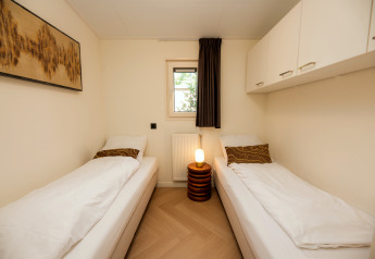 Chambre lumineuse avec deux lits simples, armoires blanches et décoration moderne à Veluwepark de Bosgraaf.