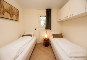 Habitación luminosa con dos camas individuales, armarios blancos y decoración moderna en Veluwepark de Bosgraaf.