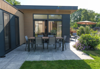 Terrasse moderne du lodge Essenburgh avec mobilier de jardin à Veluwepark de Bosgraaf, Pays-Bas, cadre verdoyant.