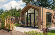 Modernes Tiny House mit Terrasse, Glasfassade und Hängesessel im Veluwepark de Bosgraaf, Niederlande.