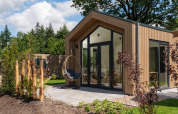 Modern tiny house called Tiny Lodge with patio, glass doors, and outdoor hanging chair at Veluwepark de Bosgraaf.