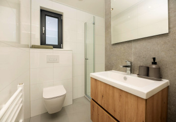 Modernes, kleines Badezimmer in einem Tiny House mit Wandtoilette, Holzwaschbecken und Dusche.
