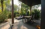 Terrasse extérieure de Sand Lodge Comfort au Veluwepark de Bosgraaf, Pays-Bas, avec table et transats.