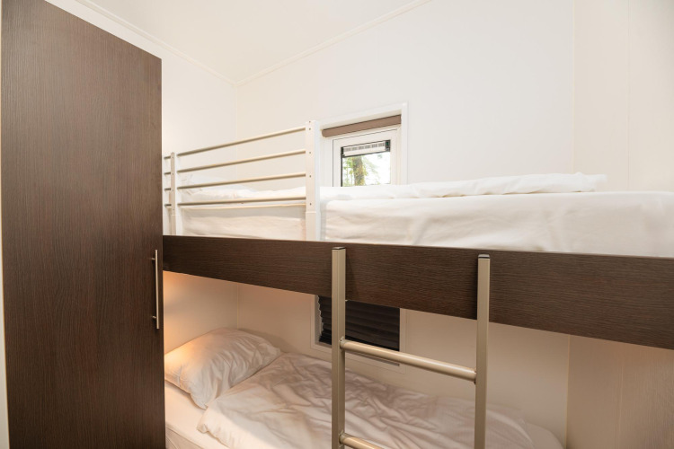 Modern bunk bed with wooden and white details in a room at Sand Lodge Comfort, Veluwepark de Bosgraaf.