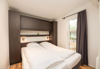 Camera da letto al Sand Lodge Comfort di Veluwepark de Bosgraaf nei Paesi Bassi con letto doppio e armadi.