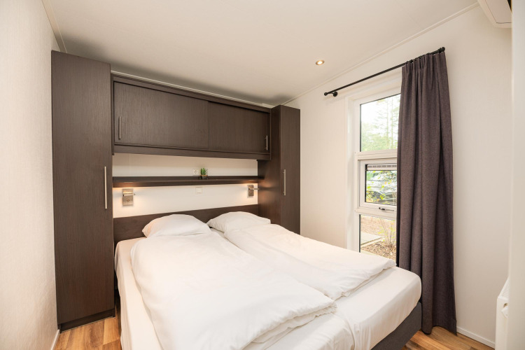Bedroom at Sand Lodge Comfort in Veluwepark de Bosgraaf, Netherlands, with double bed and cabinets.